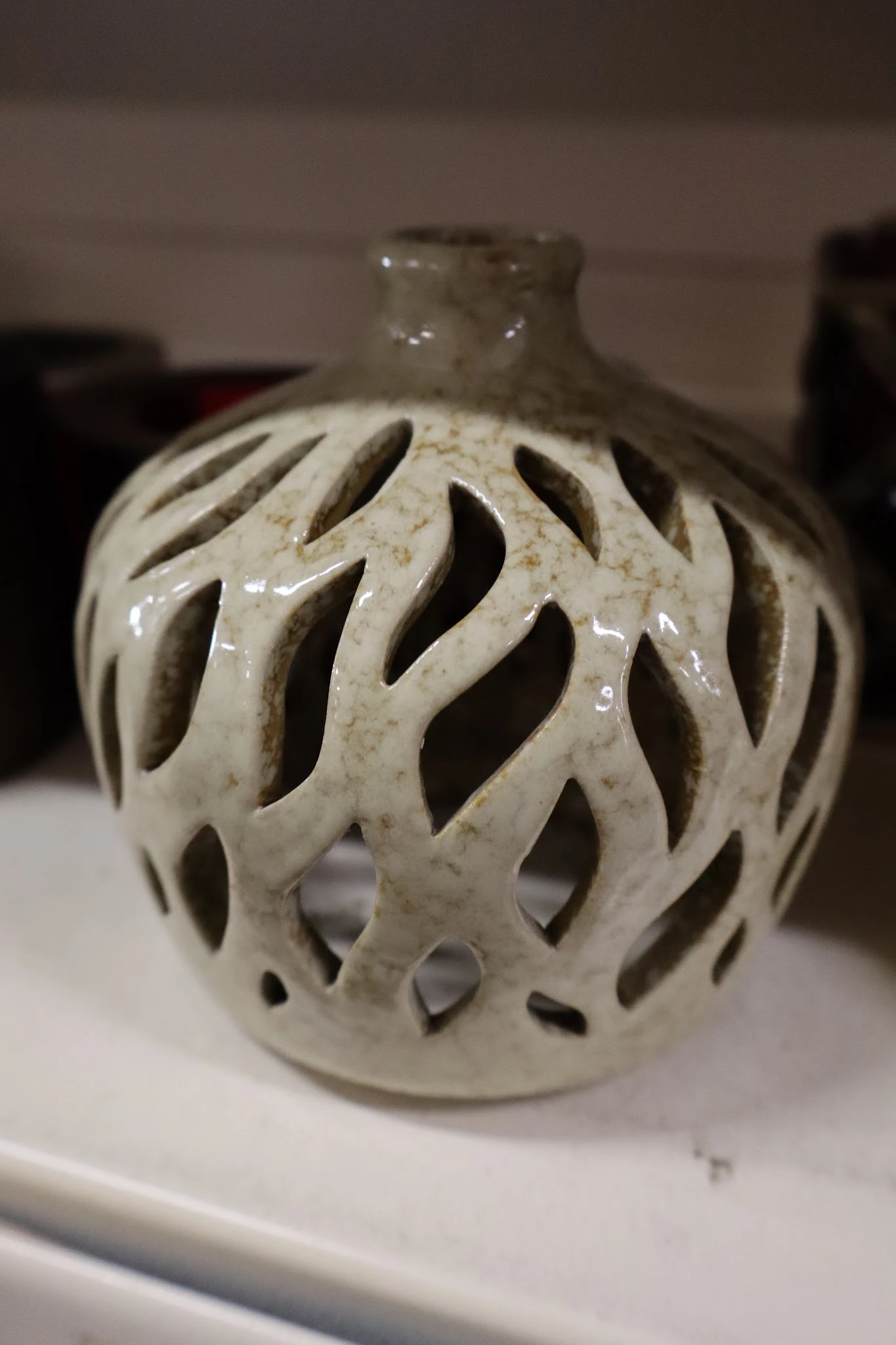 Close-up van een wit/crèmekleurig decoratief object met opengewerkte bladmotieven