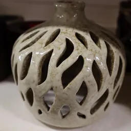 Close-up van een wit/crèmekleurig decoratief object met opengewerkte bladmotieven