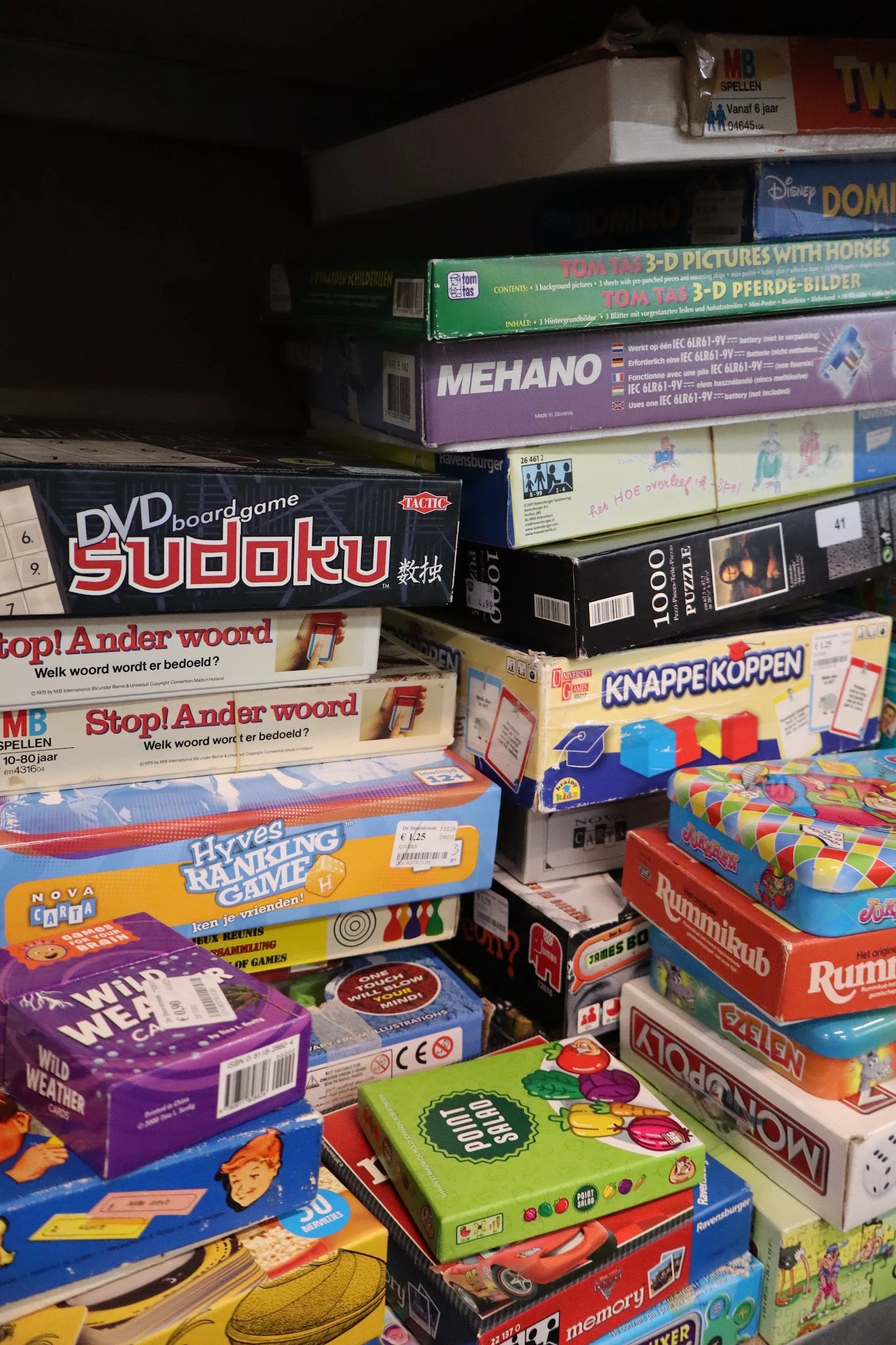 Stapel tweedehands bordspellen en puzzels waaronder Sudoku, Stop! Ander woord en Rummikub