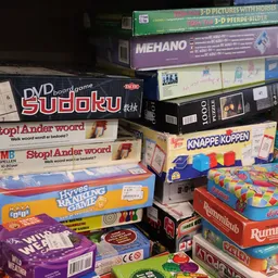 Stapel tweedehands bordspellen en puzzels waaronder Sudoku, Stop! Ander woord en Rummikub