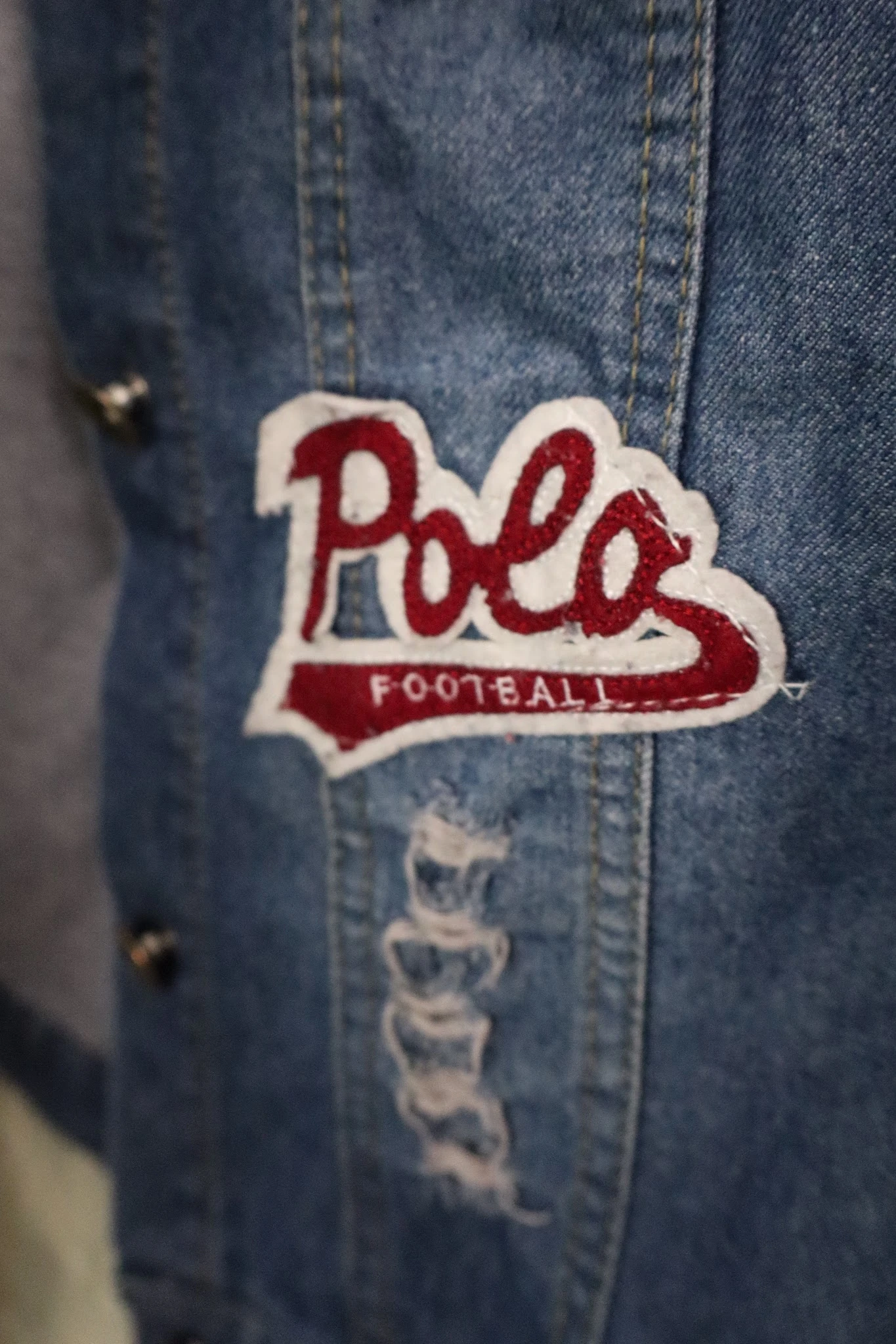 Close-up van een rood en wit Polo Football embleem op een spijkerjasje