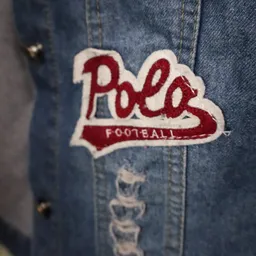 Close-up van een rood en wit Polo Football embleem op een spijkerjasje