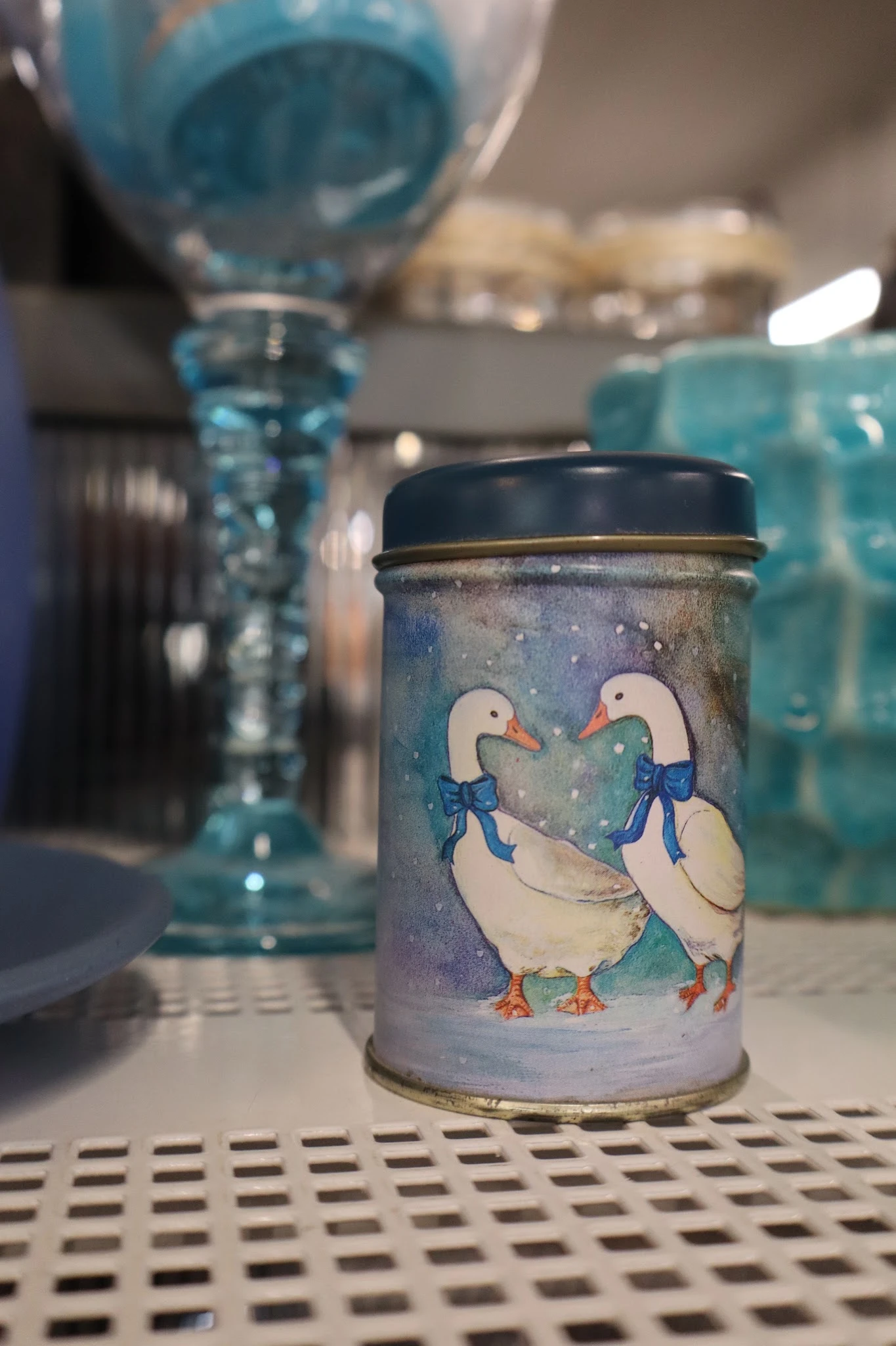 Close-up van een decoratief blikje met twee witte eenden met blauwe strikjes op grijze achtergrond