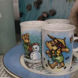 Drie witte plastic bekers met kleurige cartoonafbeeldingen van een beer en sneeuwpop