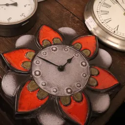 Close-up van een decoratieve bloemvormige klok met rode en witte details en metalen wijzers