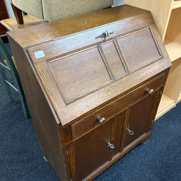 Houten sekretaire met uitklapblad en twee deuren onderin, in licht houtkleur.