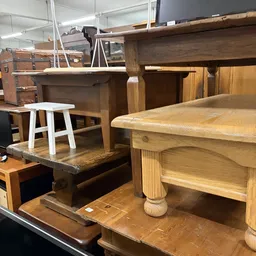 Houten meubels in een kringloopwinkel: tafels, stoelen en kastjes in verschillende stijlen