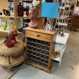 Houten kastje met wijnrek, decoratieve bustes en diverse huishoudartikelen in kringloopwinkel