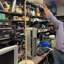 Rommelige werkruimte of opslagruimte vol elektronische apparatuur, onderdelen en dozen op planken en grond