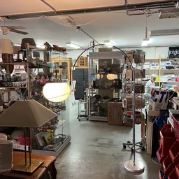Winkelvloer van kringloopwinkel met stellingen vol huishoudartikelen, lampen en meubels