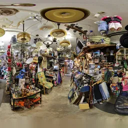 Overzicht van de kringloopwinkel met stellingen vol spullen, hangende lampen en diverse tweedehandsartikelen