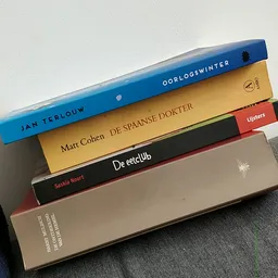 Stapel boeken met Nederlandse titels waaronder 'Oorlogswinter' van Jan Terlouw en 'De Spaanse dokter' van Matt Cohen
