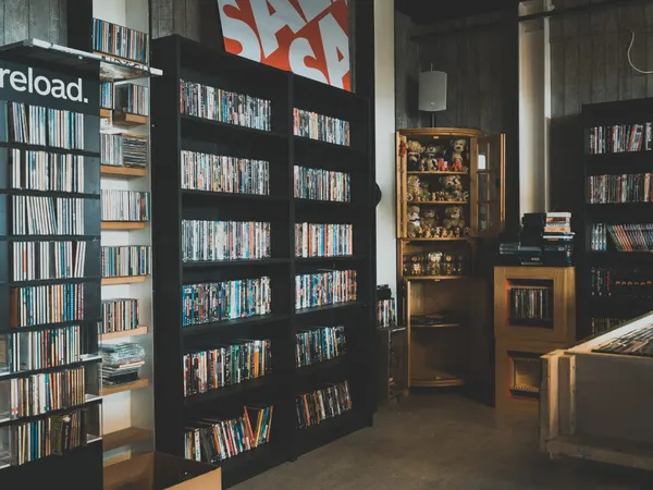 Winkelvloer met zwarte stellingen vol dvd's, boeken en verzamelobjecten in vitrinekast