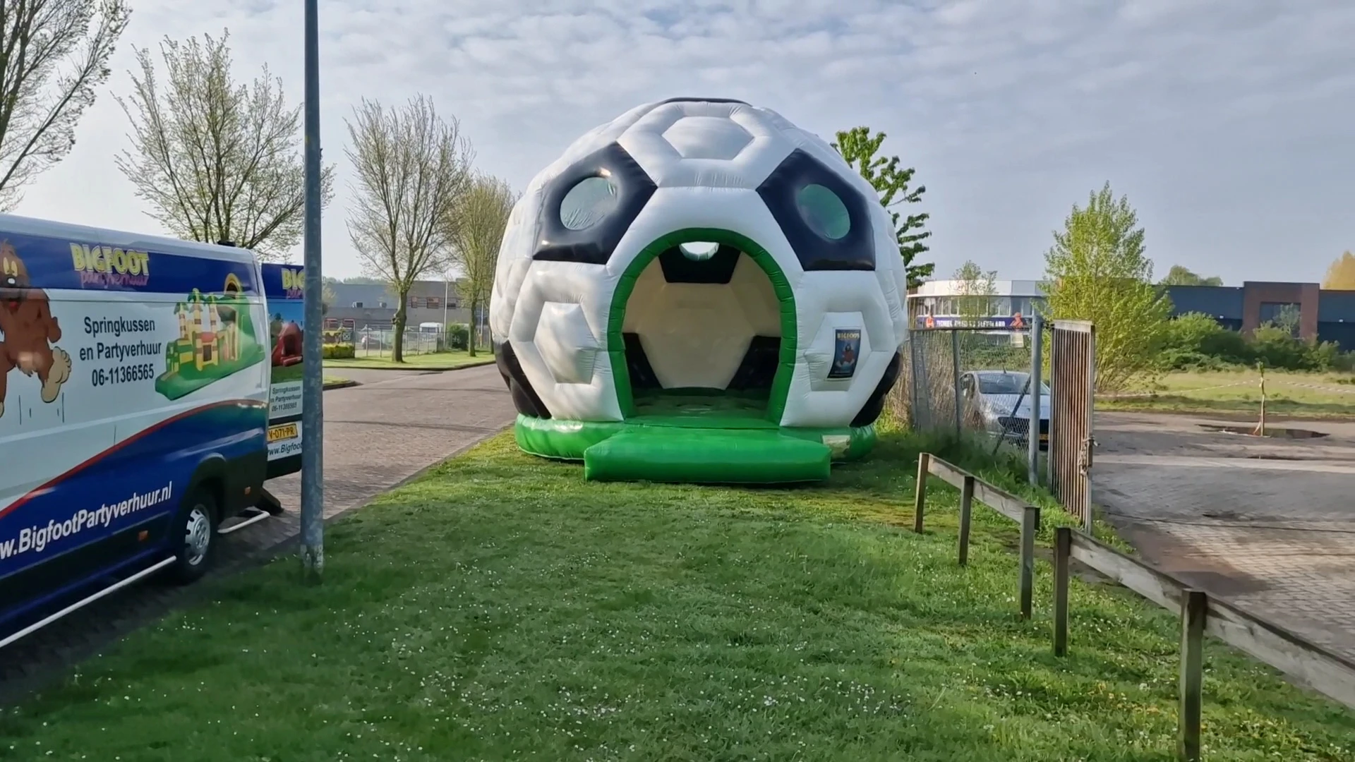 Opblaasbare voetbalvormige speelstructuur op grasveld naast kringloopwinkel