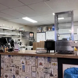 Binnenkant van een koffiehoek met espressomachine, shelves met spullen en een bestelbalies met decoraties