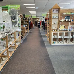 Winkelinterieur met houten stellingen, displaykasten met serviesgoed en kledingrekken langs de wanden
