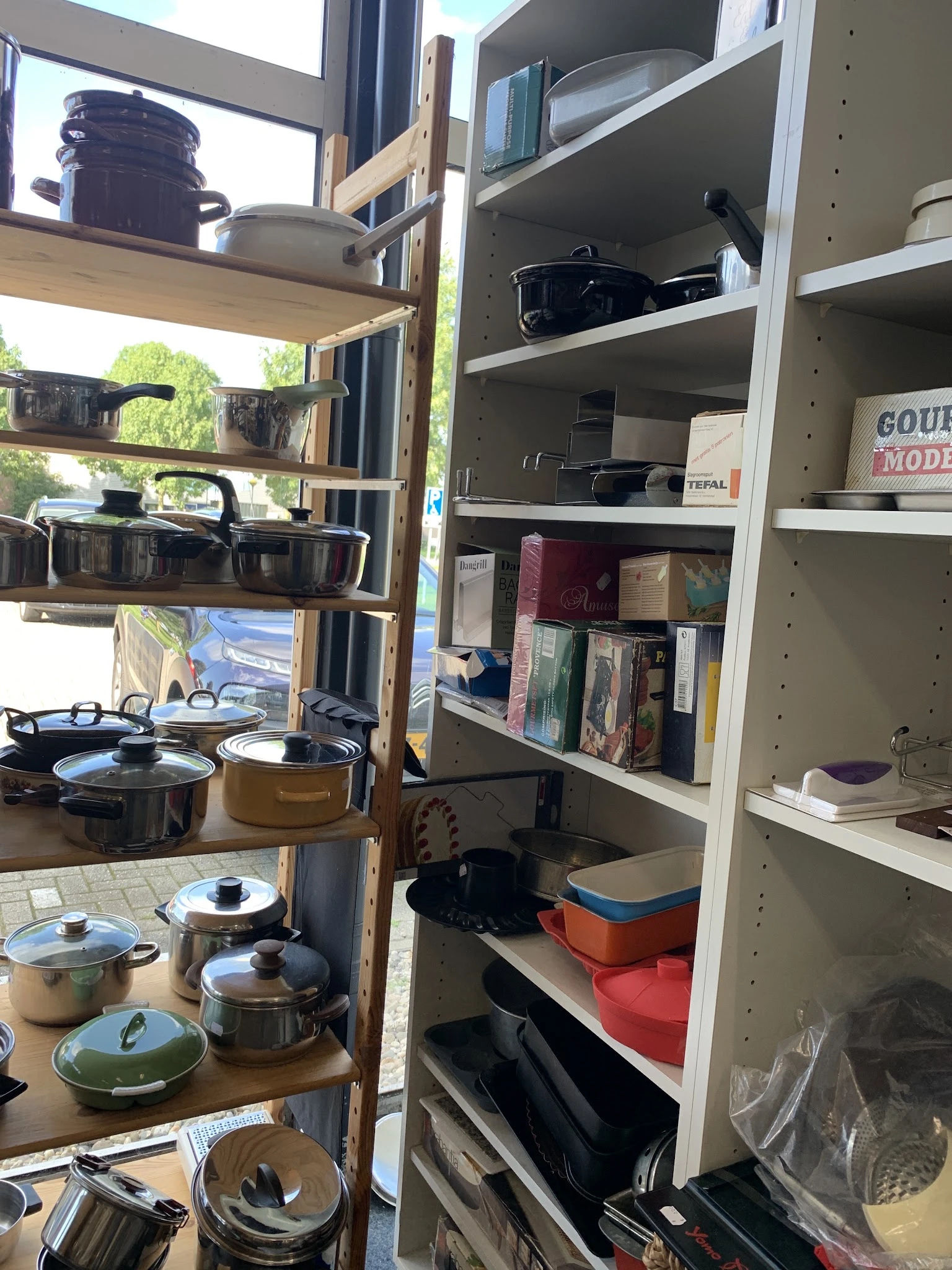 Stellingen met huishoudelijke artikelen: pannen, kookgerei, boeken en overige huisraad