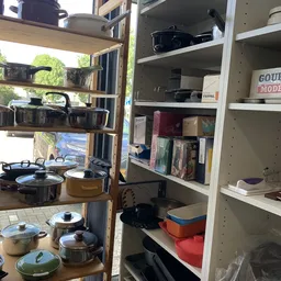 Stellingen met huishoudelijke artikelen: pannen, kookgerei, boeken en overige huisraad