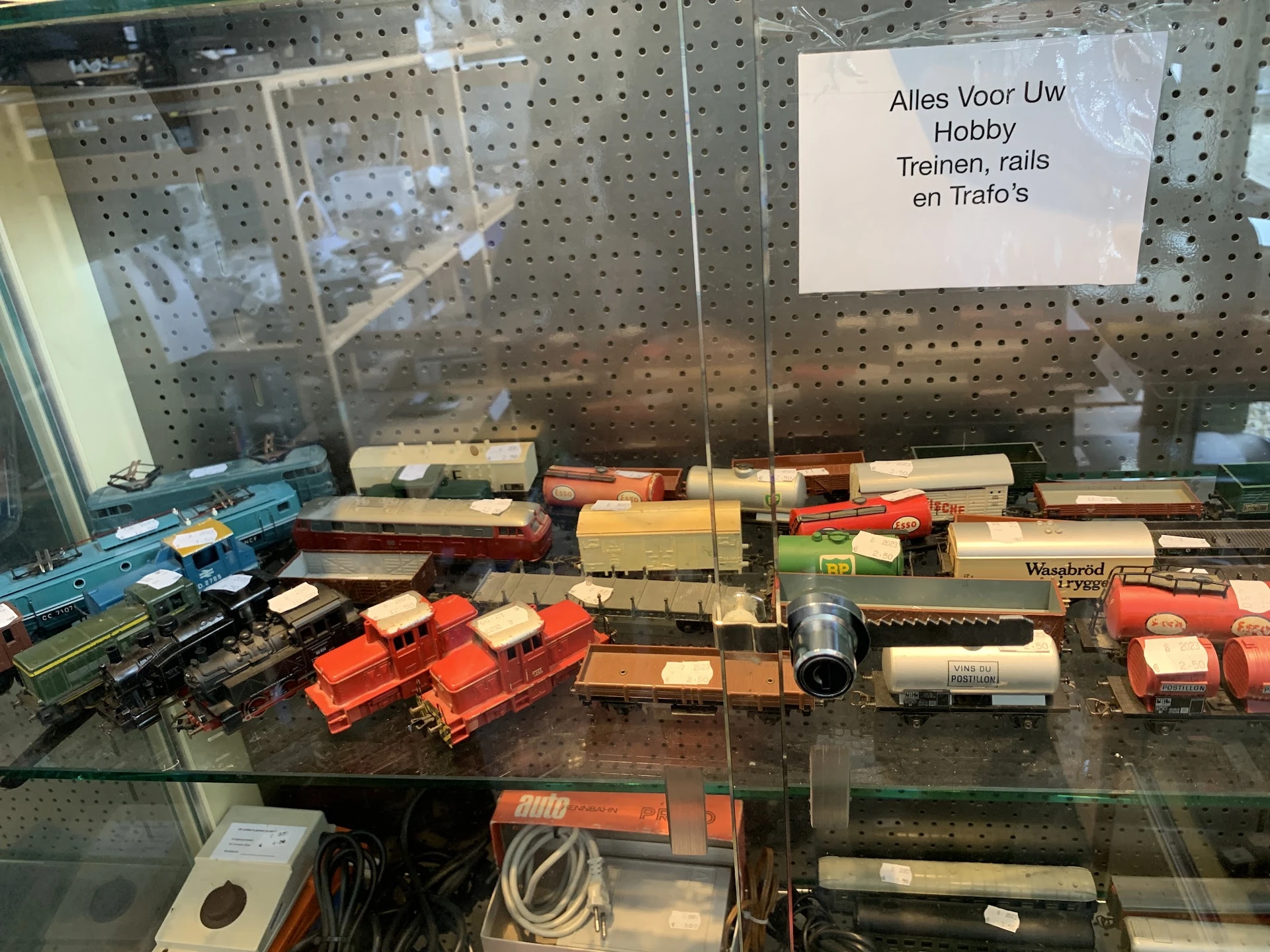 Vitrinekasten met miniatuurtreinen, rails en treinonderdelen in verschillende kleuren en formaten