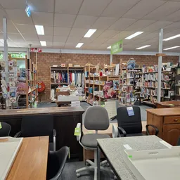 Winkelvloer met stellingen vol kleding, boeken en huishoudelijke artikelen, balie op de voorgrond