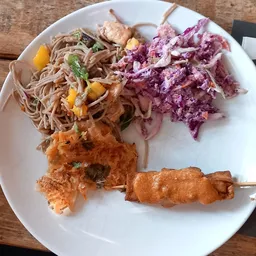 Bord met Aziatische noodles, rode coleslaw, gefrituurde hapjes en satéstokjes