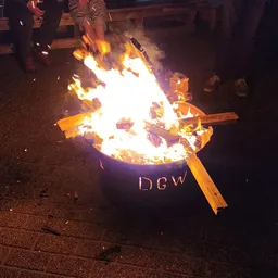 Vuur in een metalen vat met DGW-markering tijdens avondactiviteit buiten
