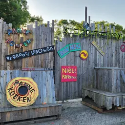 Houten gevel met kleurrijke graffiti-achtige letters en kunstwerk, trappen en ingangen zichtbaar