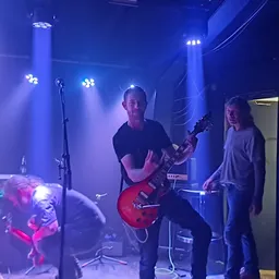 Muziekband op een verlaagd podium met blauwe verlichting en microfoon