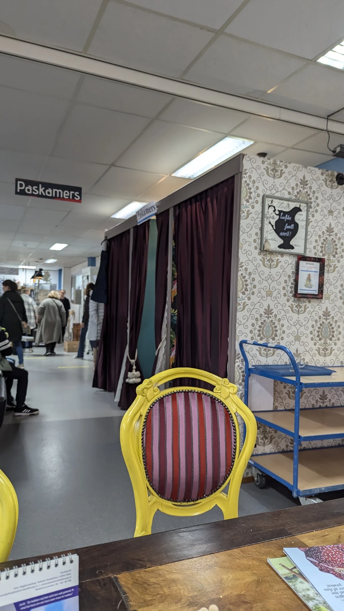 Winkelvloer met pasdokken, gordijnen en decoratieve behangwanden in een kringloopwinkel