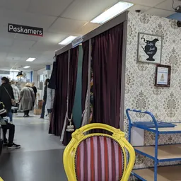 Winkelvloer met pasdokken, gordijnen en decoratieve behangwanden in een kringloopwinkel