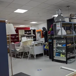 Winkelvloer met stellingen, ledikanten, kleding en huishoudartikelen in een kringloopwinkel