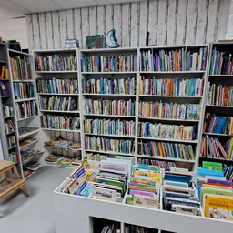 Boekenkasten met dvd's en boeken in een kringloopwinkel, met uitgestalde items op tafels vooraan