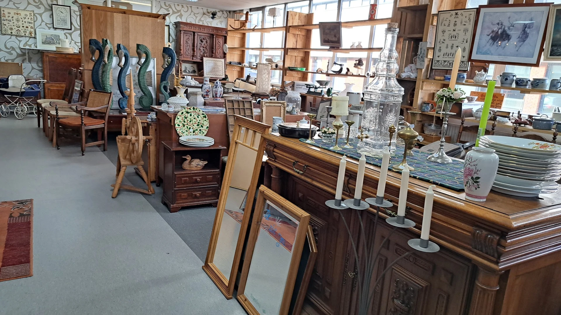 Winkelvloer met houten meubels, beeldjes, spiegels en decoratieve items uitgestald in een kringloopwinkel