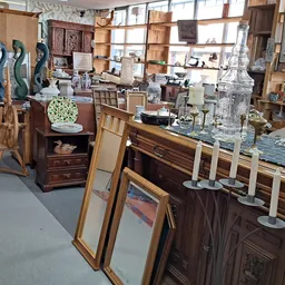 Winkelvloer met houten meubels, beeldjes, spiegels en decoratieve items uitgestald in een kringloopwinkel