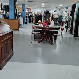 Winkelinterieur met kledingrekken, tafels met kledinguitstalling en bezoekers die winkelen