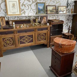 Houten dressoir met ingelegd houtwerk en decoratieve panelen, met daarnaast een houten koffer en ander antiek meubilair