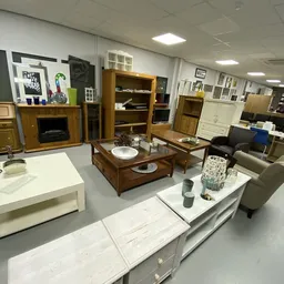 Winkelvloer met houten meubels, salontafels, kasten en witte toonbanken met huishoudartikelen