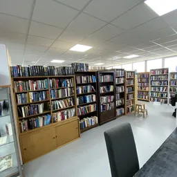 Binnenzicht van kringloopwinkel met meerdere boekenkastjes gevuld met dvd's en boeken