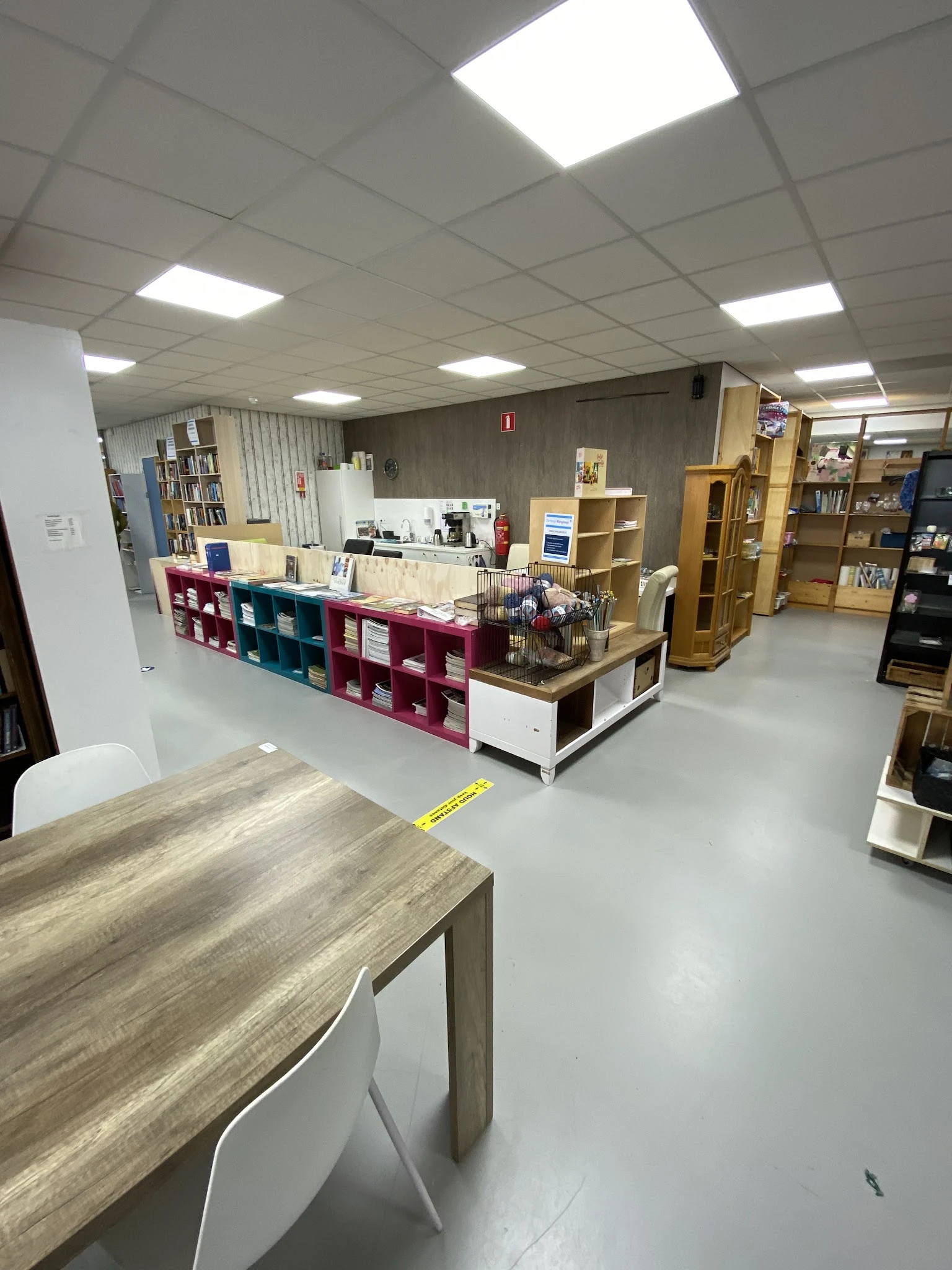 Winkelvloer met gekleurde stellingen, boekenkasten en verschillende afdelingen in een kringloopwinkel