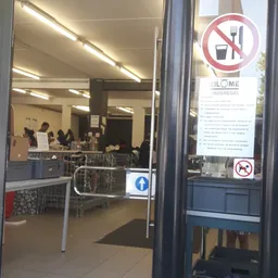 Binnenaanzicht van kringloopwinkel met stellingen, tafels en enkele klanten aan het winkelen