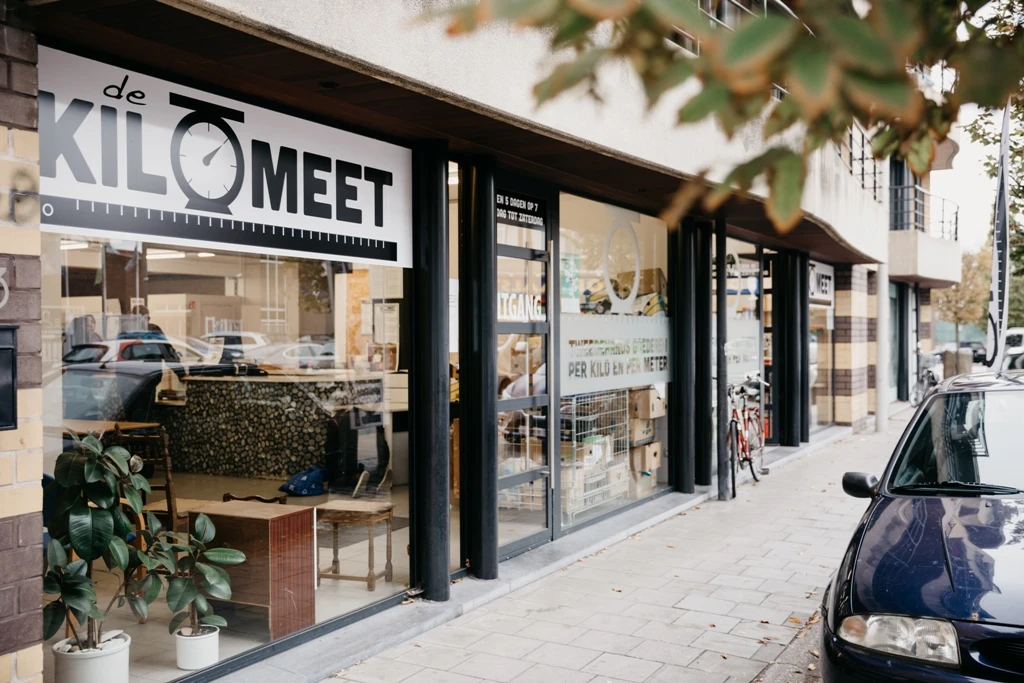 Winkelpui van kringloopwinkel met zwarte frame en grote ramen, winkelnaam duidelijk zichtbaar