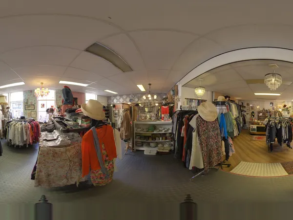 Winkelvloer van een kringloopwinkel met kledingrekken, toonbanken en vintage decoratie