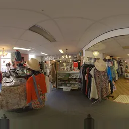 Winkelvloer van een kringloopwinkel met kledingrekken, toonbanken en vintage decoratie