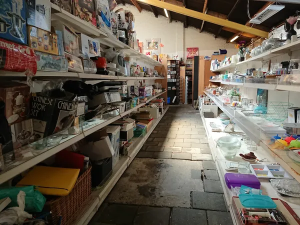 Lange gang in een kringloopwinkel met volle stellingen vol spullen aan beide zijden