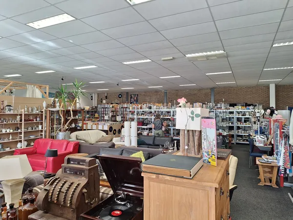 Winkelvloer van kringloopwinkel met meubels, rekken met spullen en diverse artikelen uitgestald
