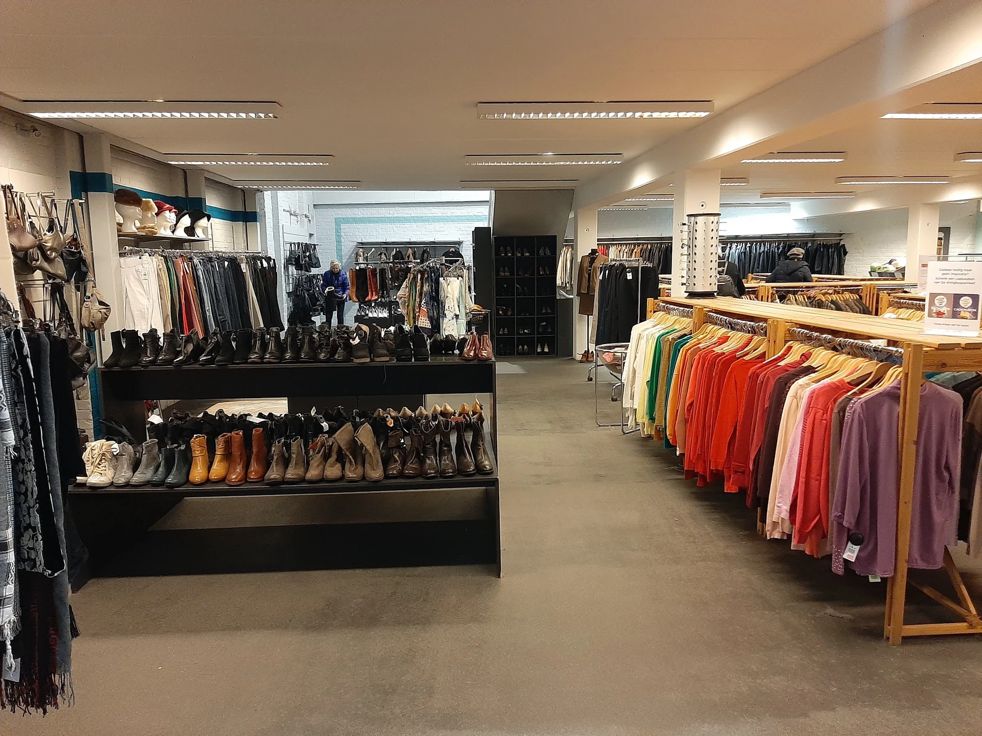 Winkelvloer met kleding- en schoenenrekken, diverse kledingstukken uitgestald op hangers en tafels