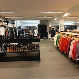 Winkelvloer met kleding- en schoenenrekken, diverse kledingstukken uitgestald op hangers en tafels