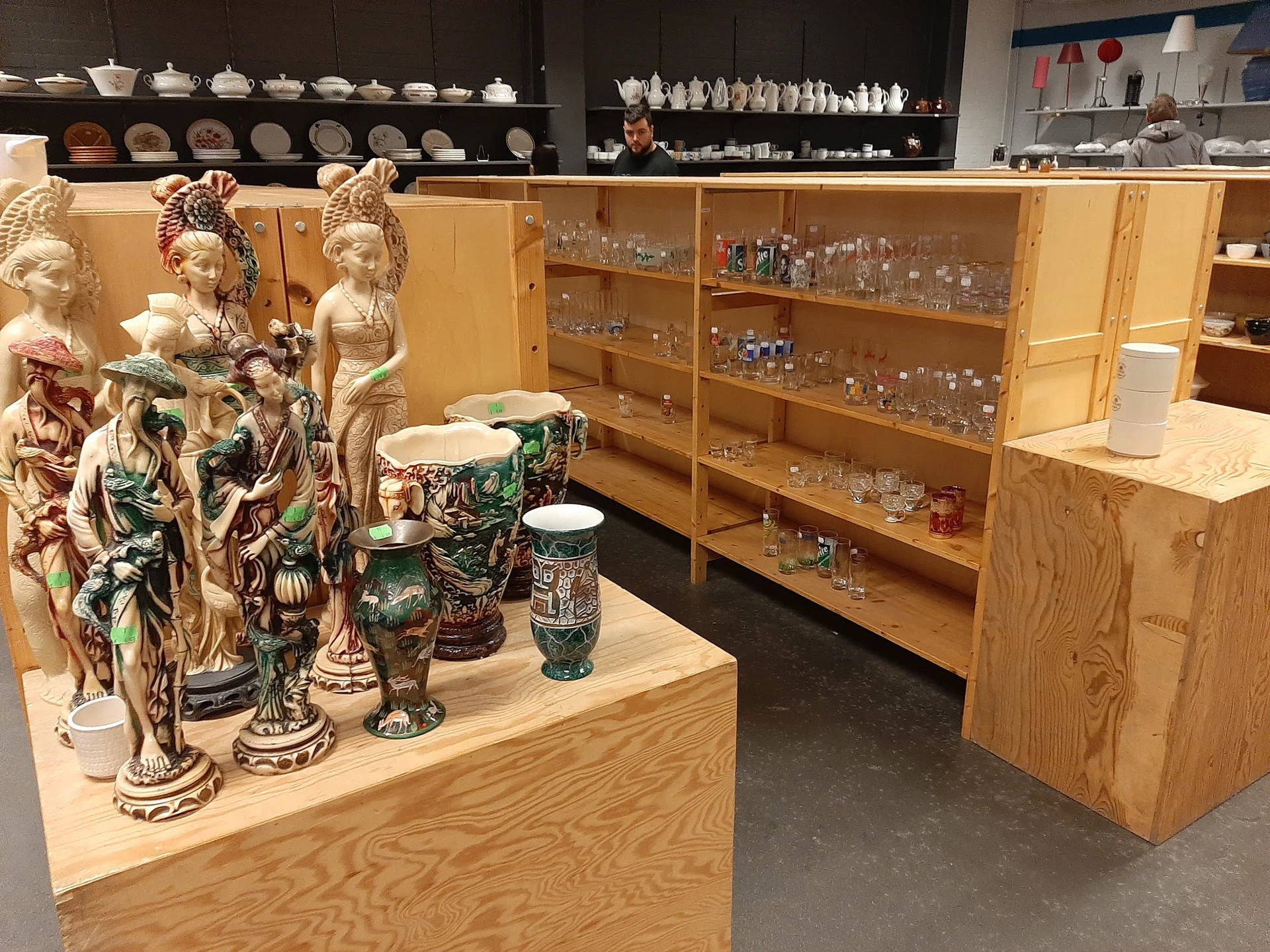Vitrinekast met decoratieve beeldjes, vazen en glaswerk in een kringloopwinkel