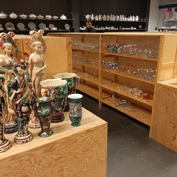 Vitrinekast met decoratieve beeldjes, vazen en glaswerk in een kringloopwinkel