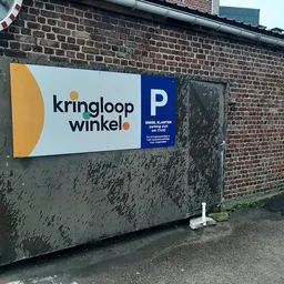 Grijze gevel met wit en blauw bord met logo en parkeerplaats-pictogram
